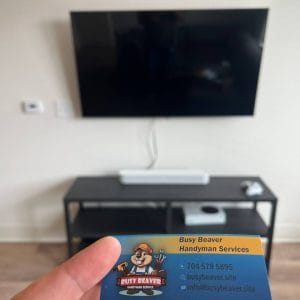 Professional handyman level checking a wall mount tv installation in Charlotte